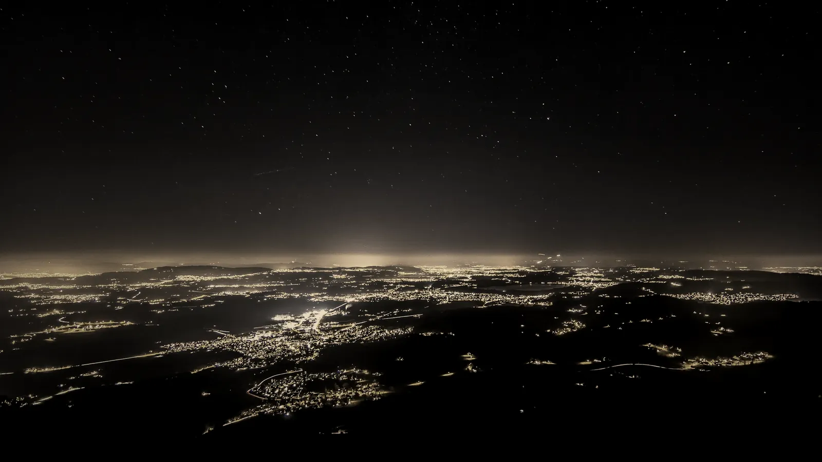 City lights spread across the land at night under a starry sky