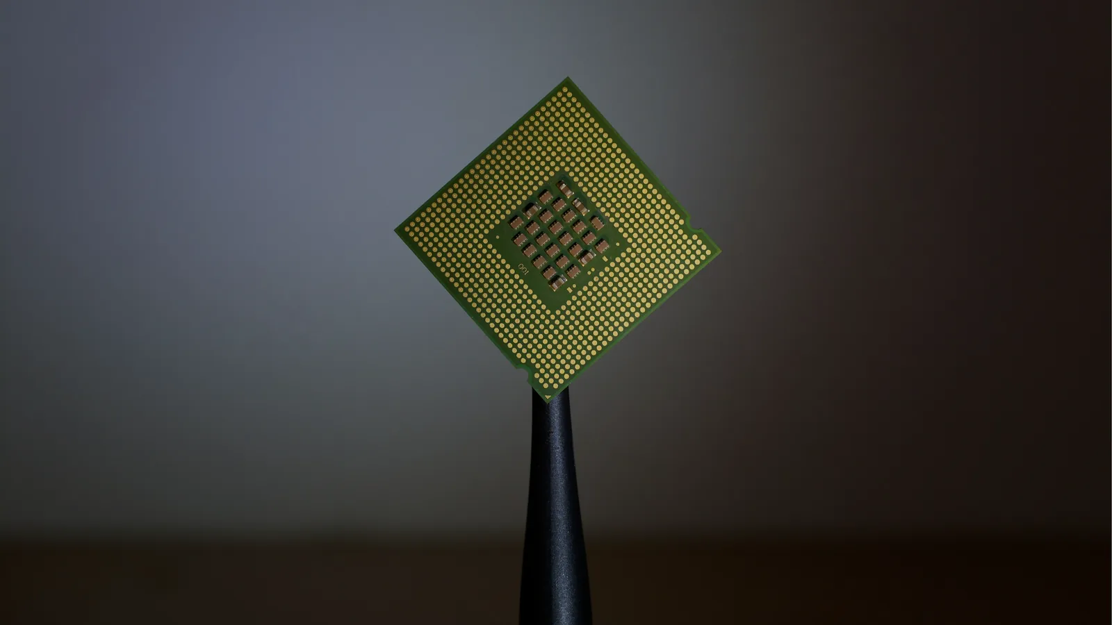 A computer processor held up in tweezers